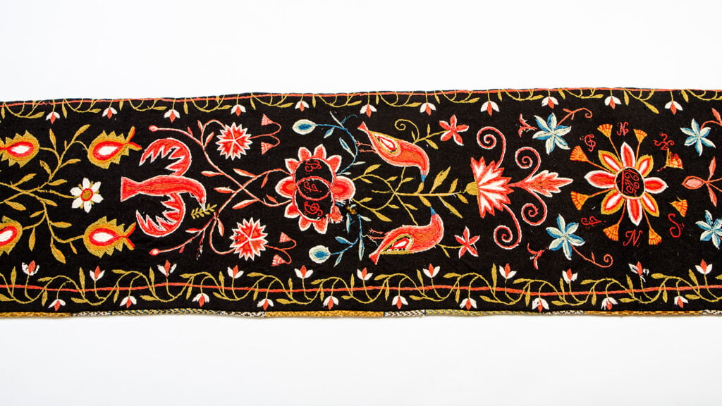 Röda broderade fåglar och blommor mot svart botten.