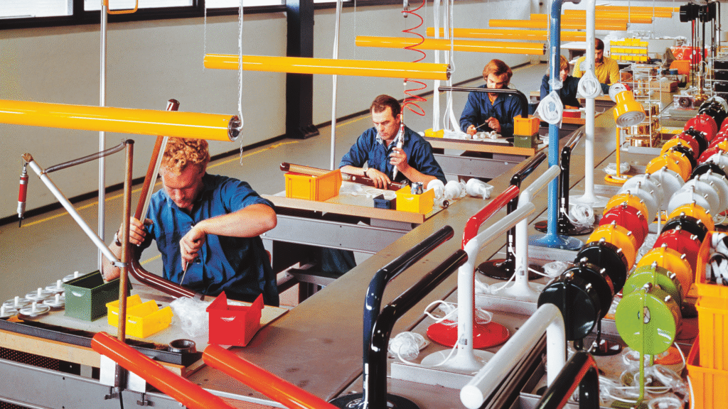 Fyra fabriksarbteare sitter och arbetar vid varsitt bord