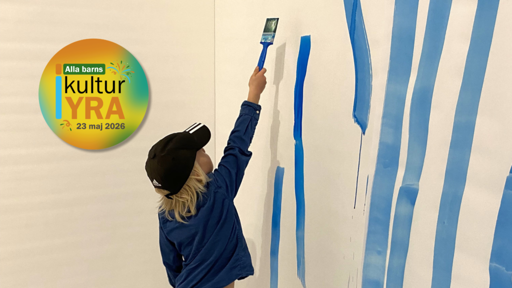 Ett barn står med ryggen emot och målar med pensel blå färg på en vit vägg.