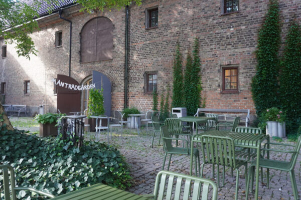 en innergård med grönskande träd och gröna utemöbler