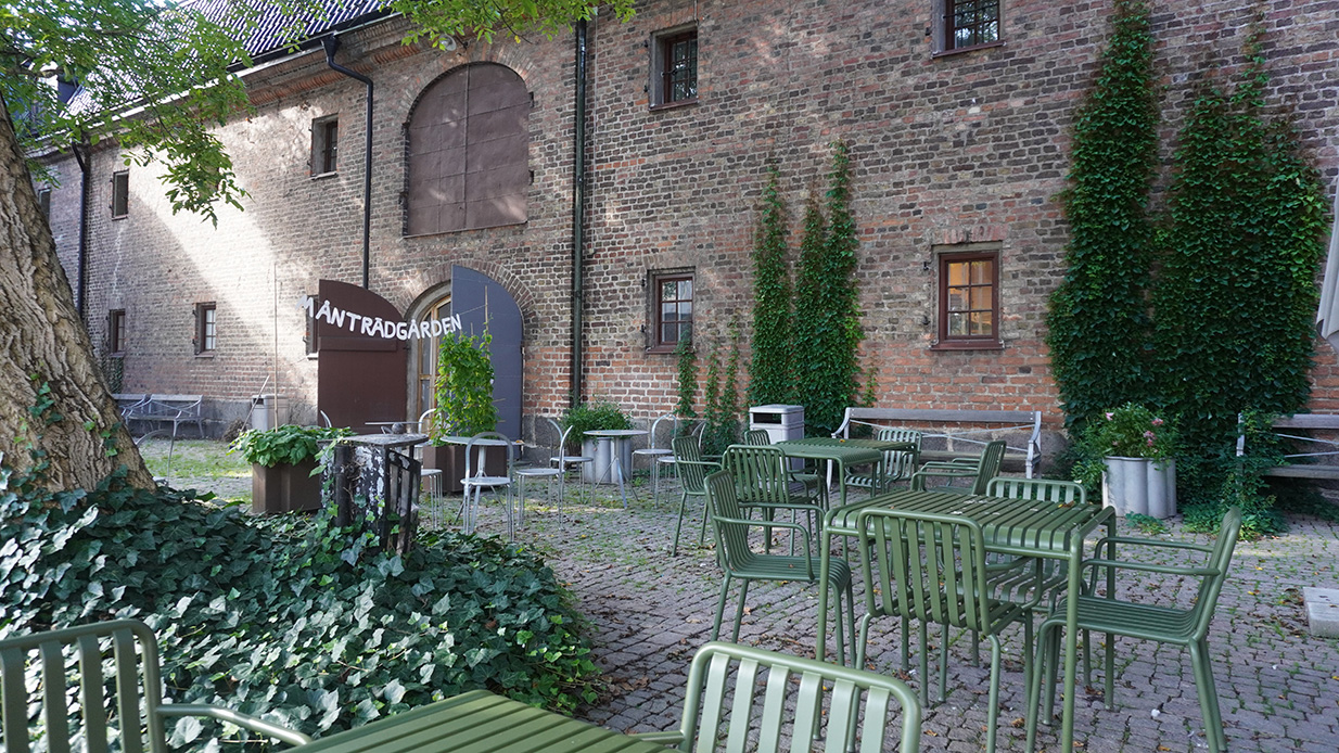 en innergård med grönskande träd och gröna utemöbler